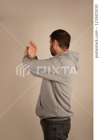 With arms crossed and fingers spread wide, a man creates a gesture of restriction or shielding. His open palms emphasize a defensive and assertive position. The image exudes caution and strength. With arms crossed and fingers spread wide, a man creates a gesture of restriction or shielding. His open palms emphasize a defensive and assertive position. The image exudes caution and strength. 123985830