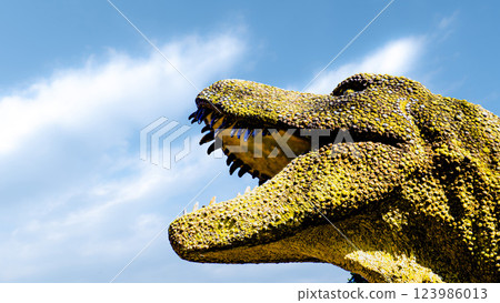 一張照片中,霸王龍的頭部雕像張開大嘴,露出鋒利的獠牙,彷彿在白雲和藍天的背景下咆哮 一張照片中,霸王龍的頭部雕像張開大嘴,露出鋒利的獠牙,彷彿在白雲和藍天的背景下咆哮 123986013