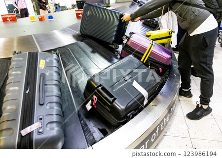 Traveler collecting luggage from the airport terminal carousel conveyer belt in arrival area 123986194