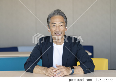 一位 60 多歲的男子戴著耳機，微笑地看著鏡頭 123986878