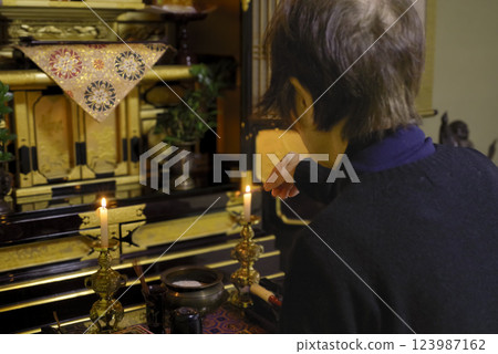 An elderly woman offering a memorial service at the Buddhist altar 123987162