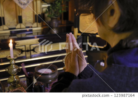 An elderly woman offering a memorial service at the Buddhist altar An elderly woman offering a memorial service at the Buddhist altar 123987164
