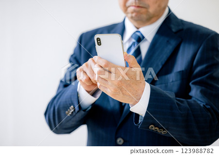 Senior businessman operating a smartphone Senior businessman operating a smartphone 123988782