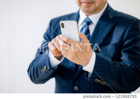 Senior businessman operating a smartphone Senior businessman operating a smartphone 123988783