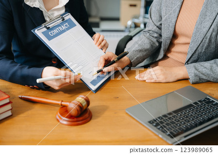 Two lawyers are discussing about contract paper, law matters determination, pointing.law and hammer Two lawyers are discussing about contract paper, law matters determination, pointing.law and hammer 123989065