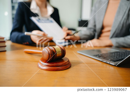 Two lawyers are discussing about contract paper, law matters determination, pointing.law and hammer Two lawyers are discussing about contract paper, law matters determination, pointing.law and hammer 123989067