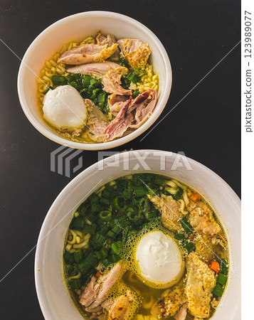 Chicken noodle soup with egg in bowl, green onion and meat in Asian food style. Top view 123989077