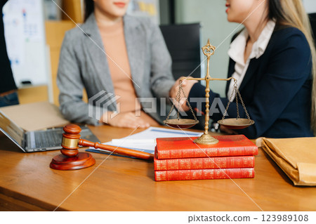 Two lawyers are discussing about contract paper, law matters determination, pointing.law and hammer Two lawyers are discussing about contract paper, law matters determination, pointing.law and hammer 123989108