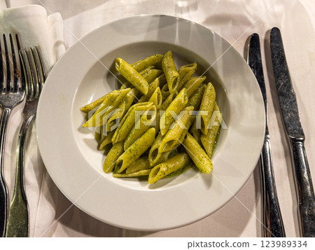 Penne pasta with pesto sauce on a white plate in a restaurant 123989334