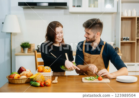 Discover a joyful couple preparing fresh vegetables, embracing healthy eating and teamwork in a vibrant kitchen Discover a joyful couple preparing fresh vegetables, embracing healthy eating and teamwork in a vibrant kitchen 123989504