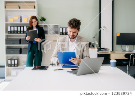 Two business workers talking on the smartphone and using laptop 123989724