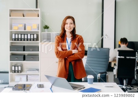 Confident business expert attractive smiling young woman typing laptop and holding digital tablet on desk Confident business expert attractive smiling young woman typing laptop and holding digital tablet on desk 123989802