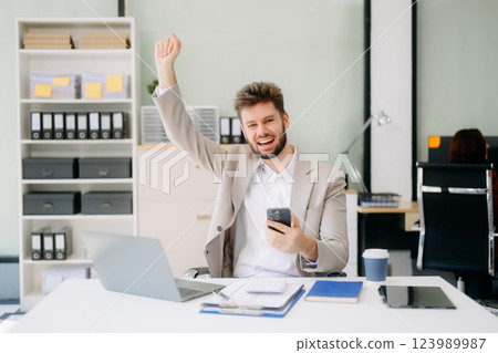 Young businessman working with working notepad, tablet and laptop documents talking on the smartphone 123989987
