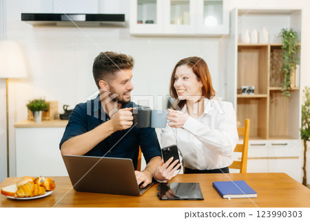 Modern couple collaborating over coffee in a cozy kitchen setting with a laptop, notebook, and breakfast. Modern couple collaborating over coffee in a cozy kitchen setting with a laptop, notebook, and breakfast. 123990303