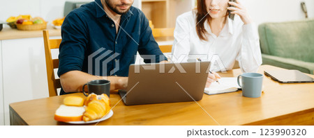 Modern couple collaborating over coffee in a cozy kitchen setting with a laptop, notebook, and breakfast. Modern couple collaborating over coffee in a cozy kitchen setting with a laptop, notebook, and breakfast. 123990320