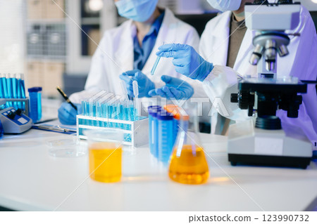 Young scientists conducting research investigations in a medical laboratory, a researcher in the foreground Young scientists conducting research investigations in a medical laboratory, a researcher in the foreground 123990732