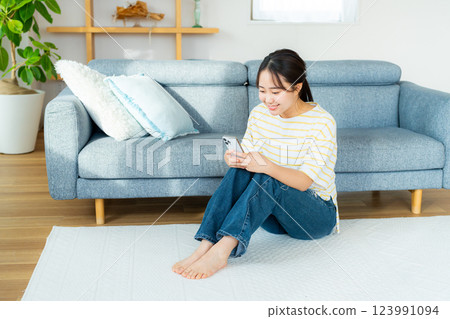 A young woman operating a smartphone in a room A young woman operating a smartphone in a room 123991094