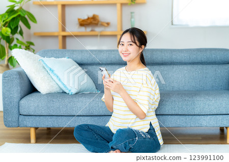 在房間裡操作智慧型手機的年輕女子 123991100