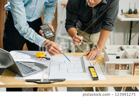 Two colleagues discussing data working and tablet, laptop with architectural project at construction site 123991275