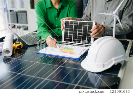Two engineers collaborate on solar and wind energy, driving clean innovation and sustainability. A vision of teamwork Two engineers collaborate on solar and wind energy, driving clean innovation and sustainability. A vision of teamwork 123991683