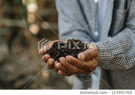 Oldman farmer holding soil in cupped hands Oldman farmer holding soil in cupped hands 123991768
