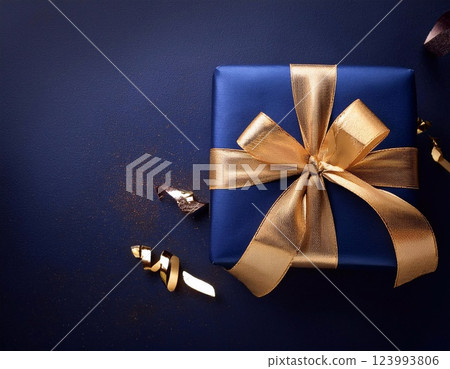 Dark blue gift box with gold ribbon on dark background. 123993806