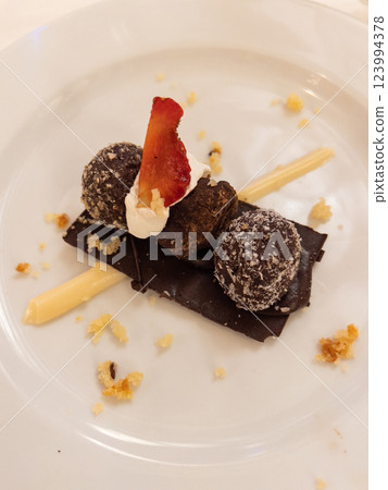 Chocolate truffles with strawberries on a white plate in a restaurant 123994378