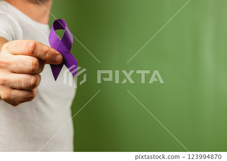 Person holding a purple ribbon symbolizing awareness and support in solidarity 123994870