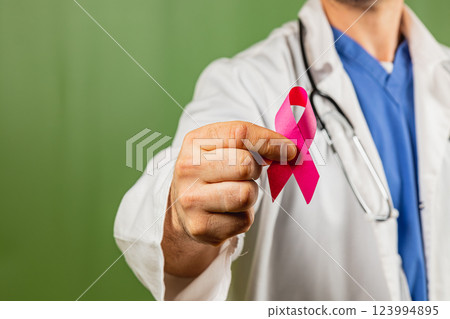 Medical professional holding a pink awareness ribbon for breast cancer support 123994895