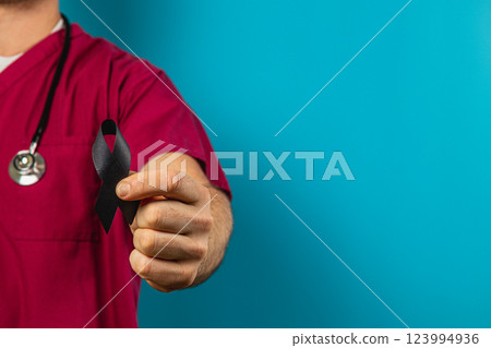 Healthcare professional holds black ribbon against a blue background Healthcare professional holds black ribbon against a blue background 123994936