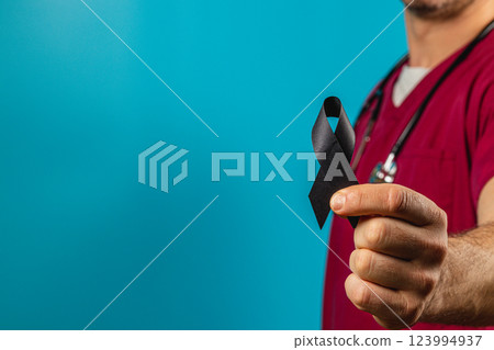 Health professional holding black ribbon in support of awareness campaign 123994937