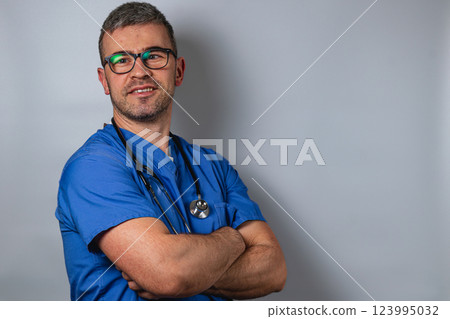 Healthcare professional in scrubs smiles confidently against gray backdrop Healthcare professional in scrubs smiles confidently against gray backdrop 123995032