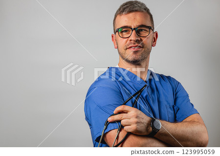 Medical professional in blue scrubs poses confidently with glasses 123995059