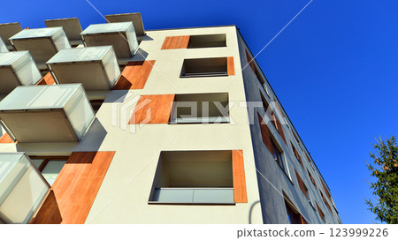 Apartment building with symmetrical modern architecture in the city. Modern apartment building on a sunny day. Facade of a modern apartment building. Bottom view. Apartment building with symmetrical modern architecture in the city. Modern apartment building on a sunny day. Facade of a modern apartment building. Bottom view. 123999226