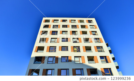 Apartment building with  symmetrical modern architecture in the city. Modern apartment building on a sunny day. Facade of a modern apartment building. Bottom view.  123999236