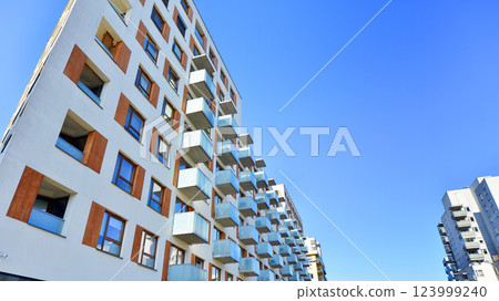 Apartment building with  symmetrical modern architecture in the city. Modern apartment building on a sunny day. Facade of a modern apartment building. Bottom view.  123999240