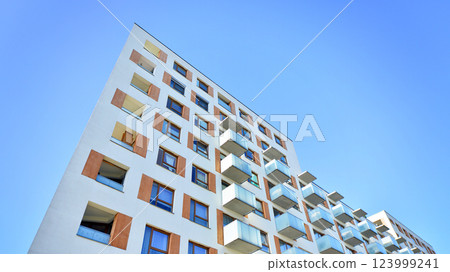 Apartment building with symmetrical modern architecture in the city. Modern apartment building on a sunny day. Facade of a modern apartment building. Bottom view. Apartment building with symmetrical modern architecture in the city. Modern apartment building on a sunny day. Facade of a modern apartment building. Bottom view. 123999241