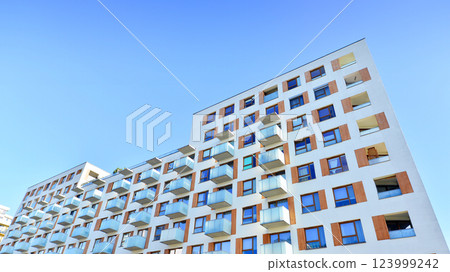 Apartment building with symmetrical modern architecture in the city. Modern apartment building on a sunny day. Facade of a modern apartment building. Bottom view. Apartment building with symmetrical modern architecture in the city. Modern apartment building on a sunny day. Facade of a modern apartment building. Bottom view. 123999242