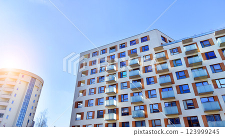 Apartment building with  symmetrical modern architecture in the city. Modern apartment building on a sunny day. Facade of a modern apartment building. Bottom view.  123999245