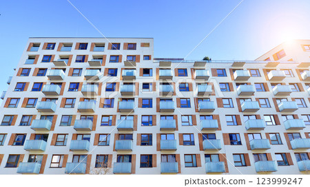 Apartment building with  symmetrical modern architecture in the city. Modern apartment building on a sunny day. Facade of a modern apartment building. Bottom view.  123999247