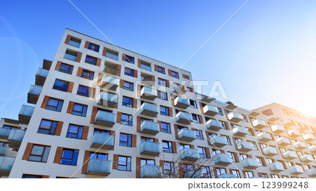 Apartment building with  symmetrical modern architecture in the city. Modern apartment building on a sunny day. Facade of a modern apartment building. Bottom view.  123999248