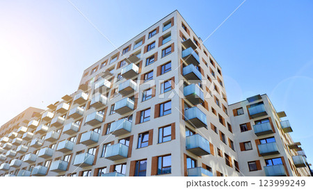 Apartment building with  symmetrical modern architecture in the city. Modern apartment building on a sunny day. Facade of a modern apartment building. Bottom view.  123999249