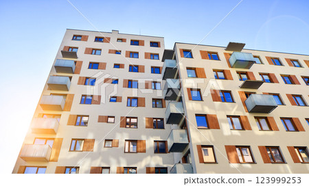 Apartment building with  symmetrical modern architecture in the city. Modern apartment building on a sunny day. Facade of a modern apartment building. Bottom view.  123999253