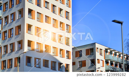 Apartment building with  symmetrical modern architecture in the city. Modern apartment building on a sunny day. Facade of a modern apartment building. Bottom view.  123999282