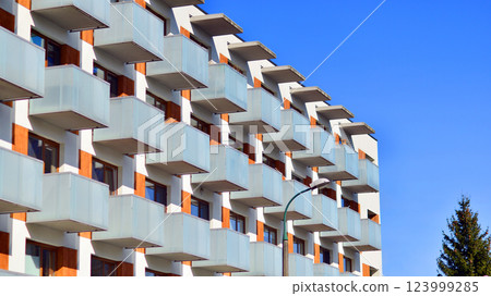 Apartment building with symmetrical modern architecture in the city. Modern apartment building on a sunny day. Facade of a modern apartment building. Bottom view. Apartment building with symmetrical modern architecture in the city. Modern apartment building on a sunny day. Facade of a modern apartment building. Bottom view. 123999285