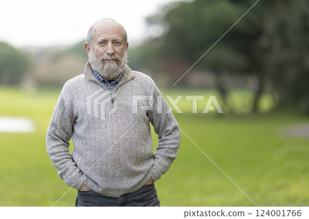 Confident senior man standing in park with hands in pockets Confident senior man standing in park with hands in pockets 124001766