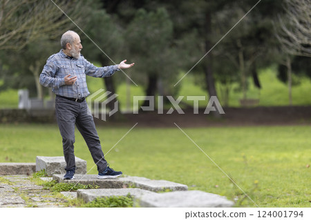 Senior man practicing tai chi chuan in a public park Senior man practicing tai chi chuan in a public park 124001794