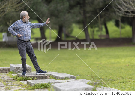 Senior man practicing tai chi in a peaceful park Senior man practicing tai chi in a peaceful park 124001795