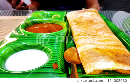 South indian food crispy Masala Dosa with sambar and chutney on banana leaf style plate 124002680