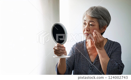拿著手鏡的老年婦女。我擔心皺紋和瑕疵。 拿著手鏡的老年婦女。我擔心皺紋和瑕疵。 124002743